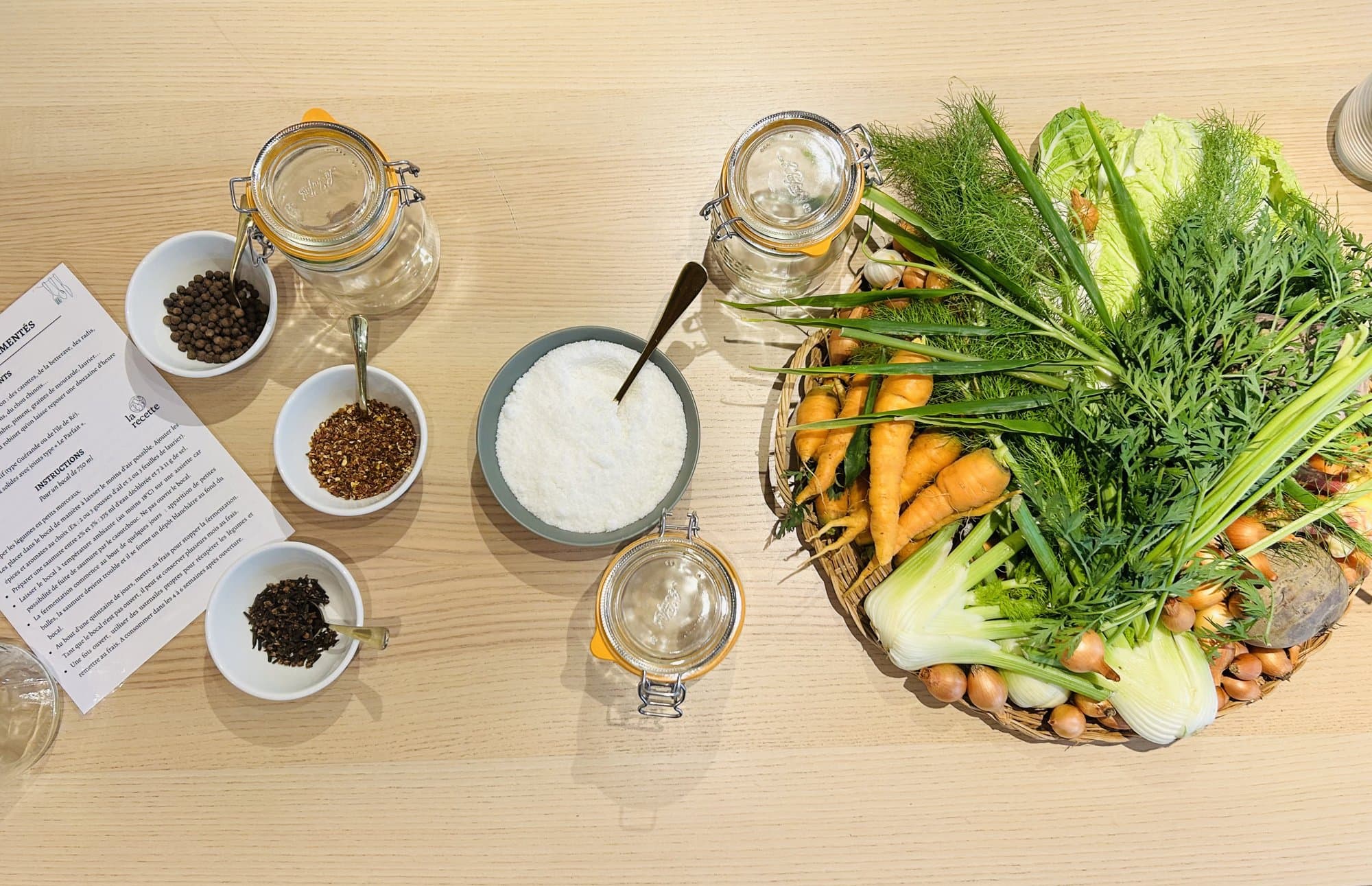 Bocaux, épices et légumes de saison posés sur une table d'atelier