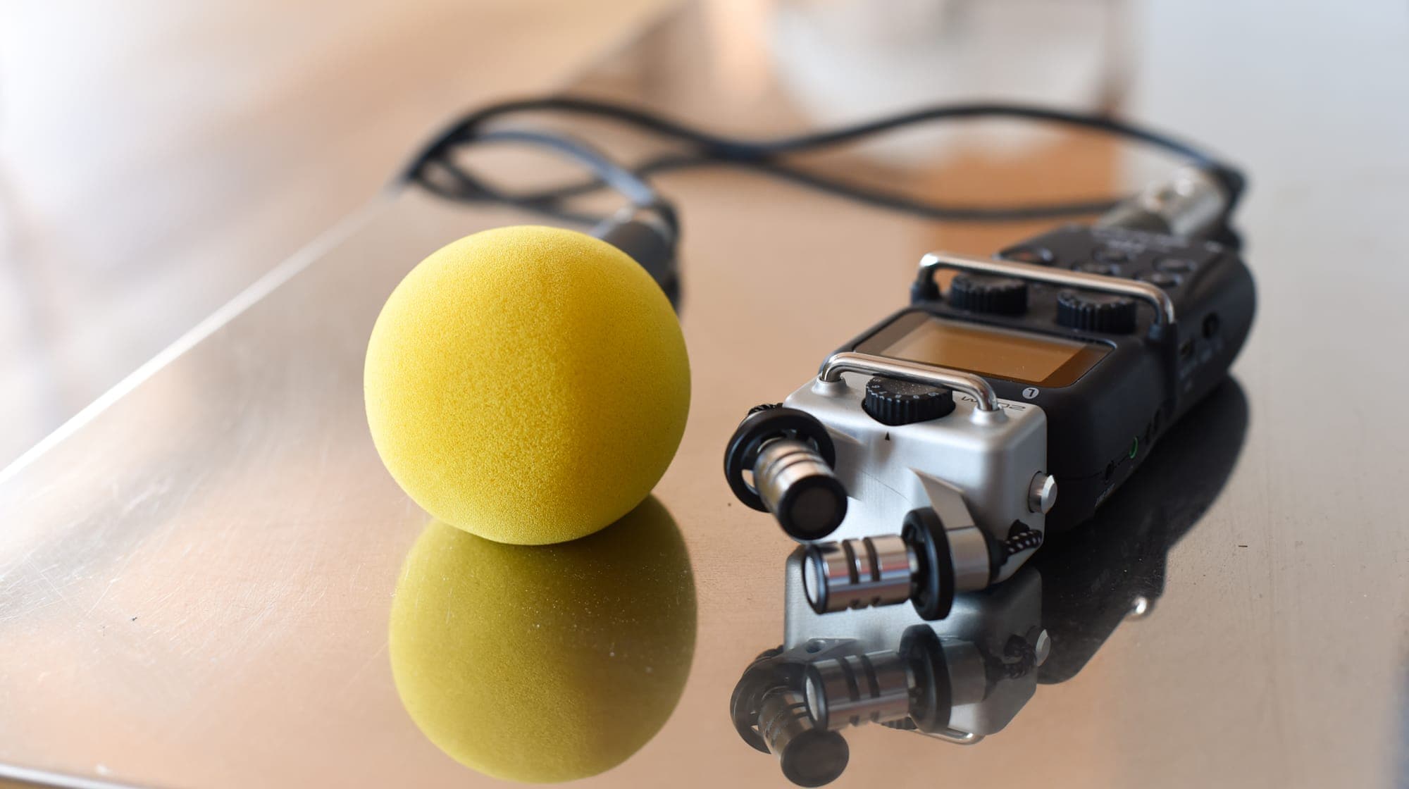 Micro à bonnette jaune et enregistreur audio posés sur une table
